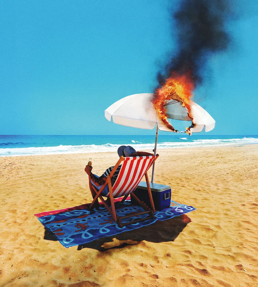 A sunbather under a beach umbrella that has caught fire